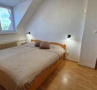 A bedroom in a two-room apartment with a double bed and a floor with a wood decor.