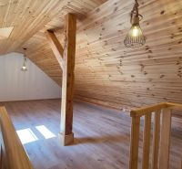 Attic space in a 2-room apartment with a wooden decor floor and wooden paneling.