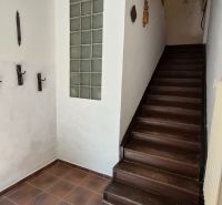A hallway with dark stairs leading to the upper floor in a 2-room apartment.