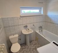 Bathroom in a 2-room apartment with a bathtub, sink, washing machine, and tiled walls.