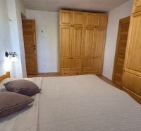 Bedroom in a 2-room apartment with wooden wardrobes, a bed, and a floor with a wooden decor.