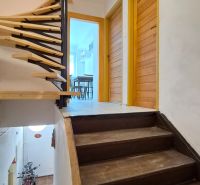 A staircase with a wooden railing leading to a 2-room apartment with a view of the entrance door.