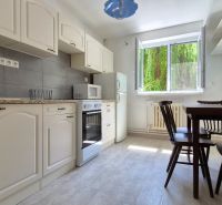 A kitchen with white cabinets and a dining table in a 2-room apartment.