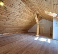 Attic room in a 2-room apartment with a wooden decor floor and wooden paneling.