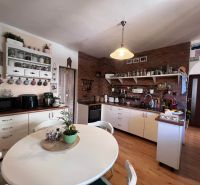 A kitchen in a family house with brick cladding and a wooden decor floor.