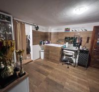 A room in a family house with a chair, trophies, and a wooden-patterned floor.
