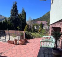 In the exterior of a family house in Švošov, there is a garden with a terrace and flower pots.