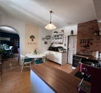 A kitchen in a family house with a wooden decor floor and a brick wall.