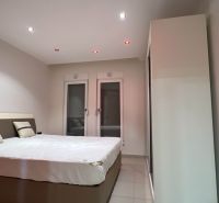 Bedroom in a vacation apartment with a large bed, white and gray walls.