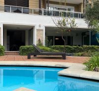 A recreational apartment in Kumköy with a terrace, pool, plenty of greenery, and a sunbed.