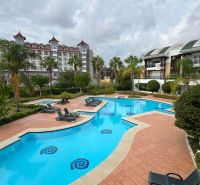 Recreational apartments in Kumköy, SIDE, with a pool surrounded by sunbeds and palm trees.