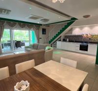 Living room of the recreational apartment with a kitchen and dining table, complemented by a staircase.