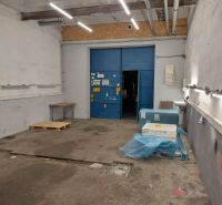 A view of a storage area with lighting, a pallet, and blue entrance doors.
