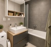 Bathroom in a 2-room apartment with a bathtub, cabinets, and a washing machine, gray tiles.