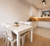 A kitchen in a 2-room apartment with a white table and a floor with a wooden decor.