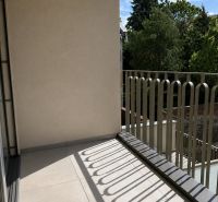 A balcony with a railing and a view of greenery in a 2-room apartment.