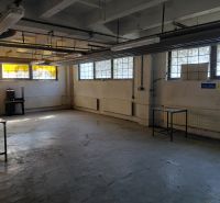 Warehouse space with concrete floor, windows, and old furniture. Warehouses and halls.