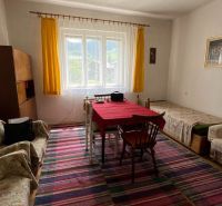 A room in a family house with a colorful carpet and a red tablecloth on the table.
