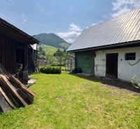 A family house in Liptovská Lúžna with a garden, a wooden shelter, and a mountain scenery.