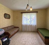 A room in a family house with sofas, patterned wallpaper, and a wooden decor floor.