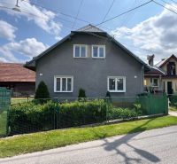 A family house in Liptovská Lúžna with a garden and a fence on a sunny day.