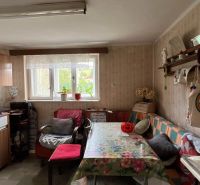 A kitchen in a family house with a floral tablecloth and simple furnishings.