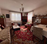 Living room in a family house with flowers, a carpet, and comfortable seating.