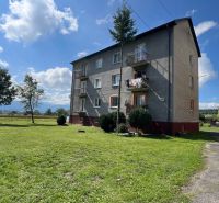 An apartment building in Pribylina surrounded by greenery and blue skies, with a view of the surrounding landscape.