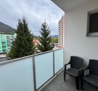 The balcony of a 3-room apartment in Ružomberok, with a view of greenery and surrounding buildings.