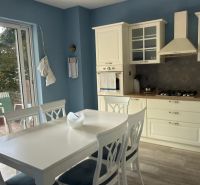 A kitchen in a family house with white furniture and access to the terrace.