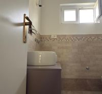 A bathroom in a family house with beige tiles and a modern sink.