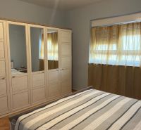 Bedroom in a family house with a bed, wardrobe, and window with sheer curtains.