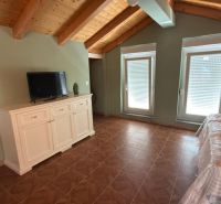 The attic in the family house contains a white dresser, a television, and skylights.