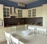 A family house kitchen with a white kitchen unit, dining table, and chairs.