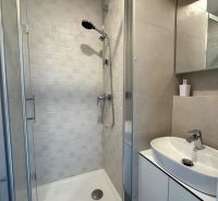 Shower corner with ceramic tiles in the bathroom of a studio apartment.
