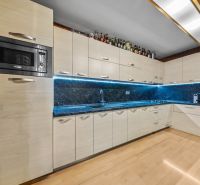 A kitchen in a family house with a wooden decor floor, built-in appliances, and LED lighting.