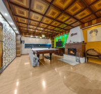 Interior of a family house with a fireplace, a pool table, and a wooden decor floor.