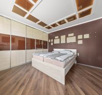Bedroom in a family house with a wood-patterned floor and a built-in wardrobe.