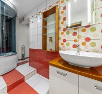 A bathroom in a family house with colorful tiles, a shower, and a sink.