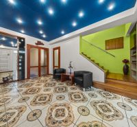 Bright room in a family house with armchairs, staircase, and decorative tiles.