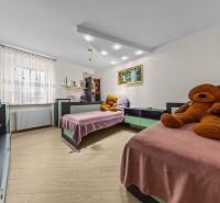 Children's room in a family house with two beds, plush teddy bears, and a floor with a wooden decor.