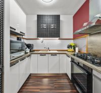 A kitchen in a family house with modern appliances and a wooden decor floor.