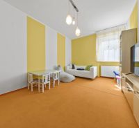 Living room with colorful walls, a sofa, a television, and a children's table in a family house.