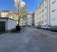 Parking lot near an apartment building in Banská Bystrica with cars and trees.