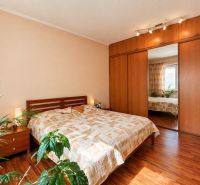 A bedroom with wood-patterned flooring, a built-in wardrobe, and a bed in a 4-room apartment.