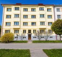 Apartment building in Banská Bystrica, yellow facade, landscaped greenery, clear sky.