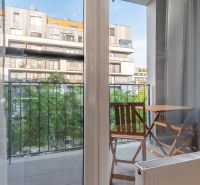 View from a 1-bedroom apartment to a balcony with a table and chairs.