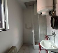 A bathroom in a family house with a window, a sink, and a water heater.