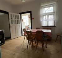 A kitchen in a family house with a wooden table, shelf, and floor with a wooden decor.