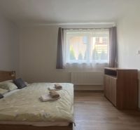 A simply furnished bedroom with a bed and a wooden decor floor in a two-room apartment.